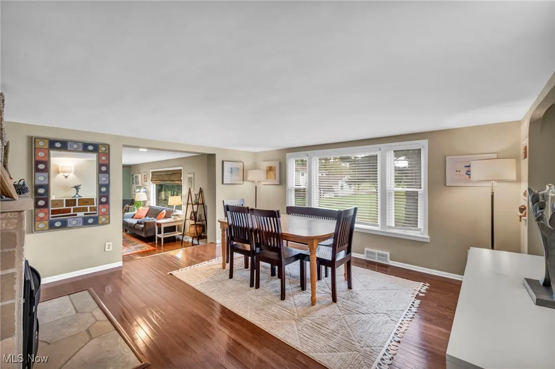 Dining area with dark hard wood finished floors and healthy amount of natural light and fireplace