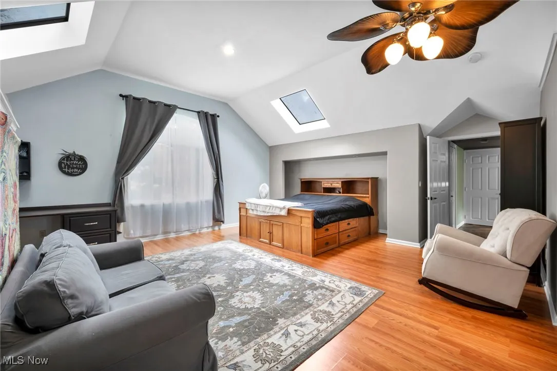 Bedroom featuring a skylight, vaulted ceiling, wood flooring, and a ceiling fan