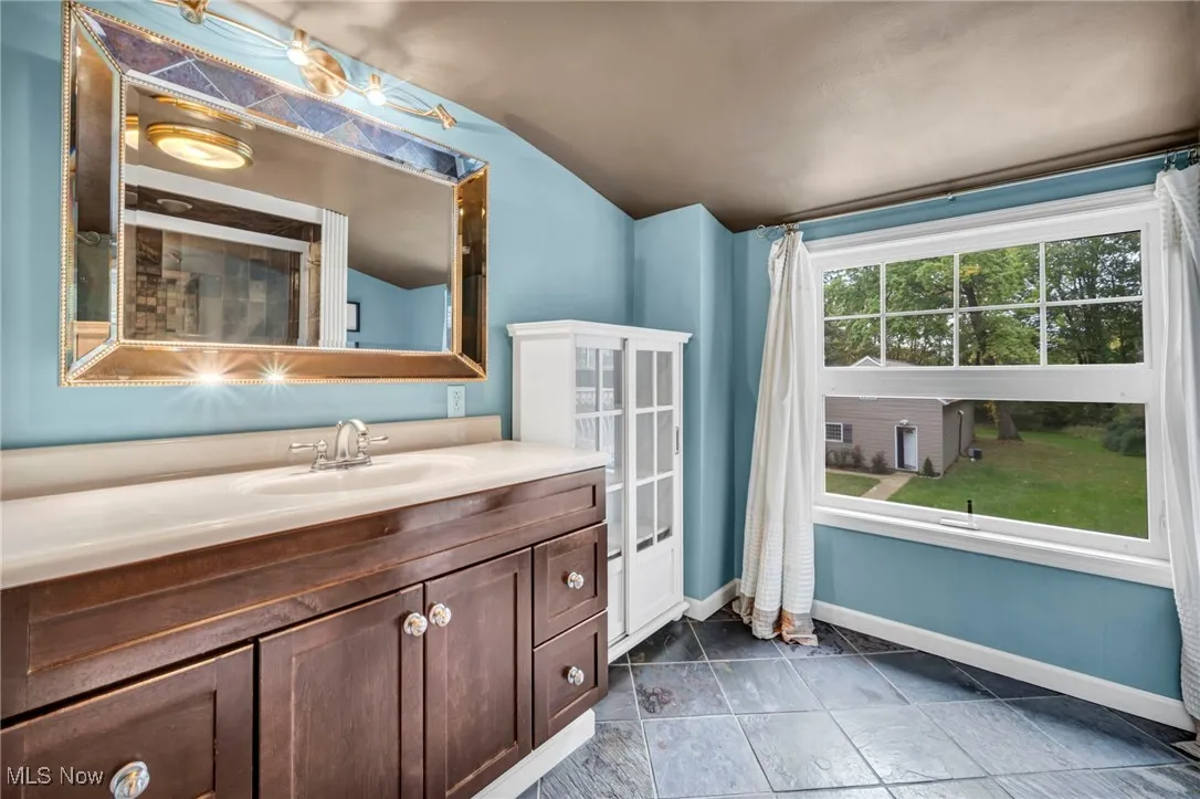 Full bathroom second floor featuring vanity, lofted ceiling, and dark stone finish floors