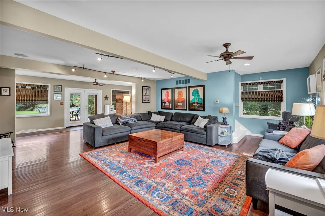 Living area featuring ceiling fan, track lighting, wood finished floors, french doors, and beamed ceiling