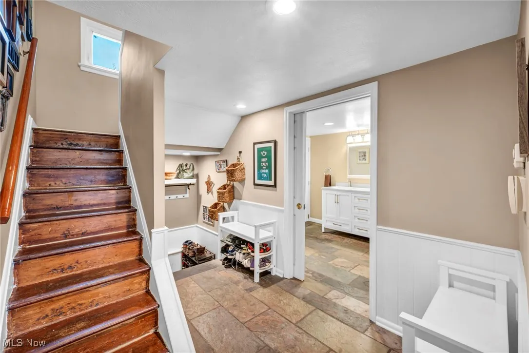 Stairway featuring slate tile floors, a wainscoted wall, and recessed lighting