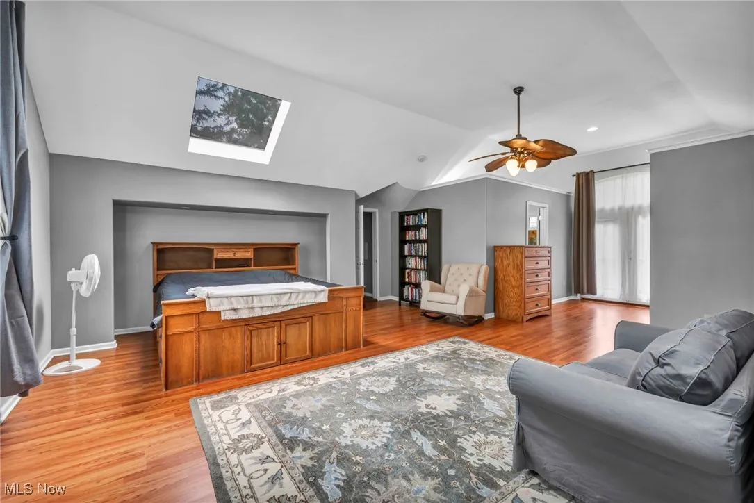 Bedroom with a skylight, light wood-style flooring, lofted ceiling, and a ceiling fan