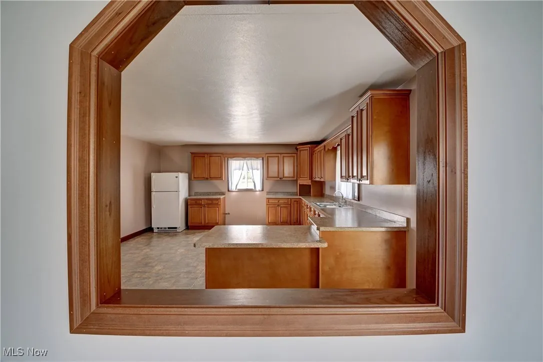 Kitchen featuring freestanding refrigerator, light countertops, and brown cabinetry