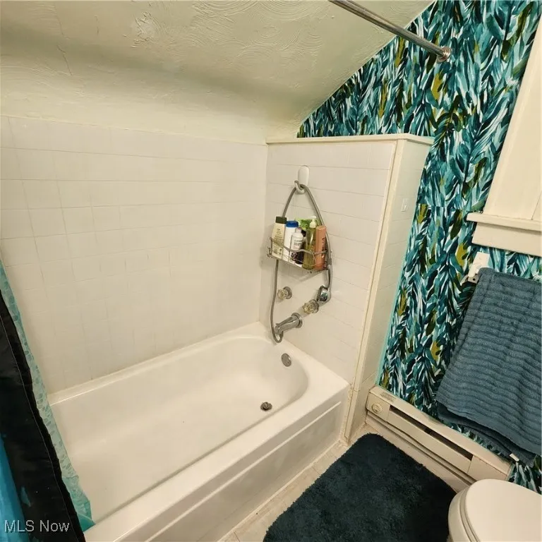 Full bathroom with a stall shower, a baseboard radiator, tile patterned flooring, a tub, and wallpapered walls