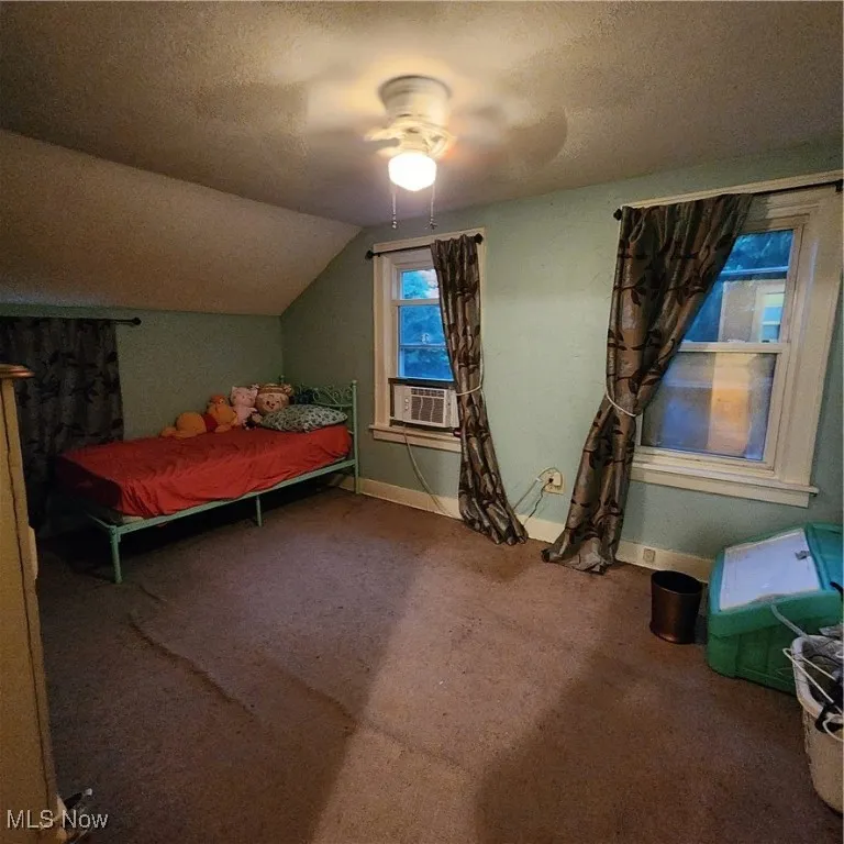 Bedroom featuring a textured ceiling, carpet, ceiling fan, lofted ceiling, and cooling unit