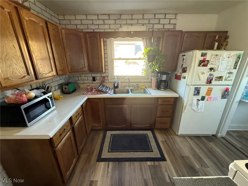 Kitchen featuring light countertops, freestanding refrigerator, dark wood-style floors, and stainless steel microwave