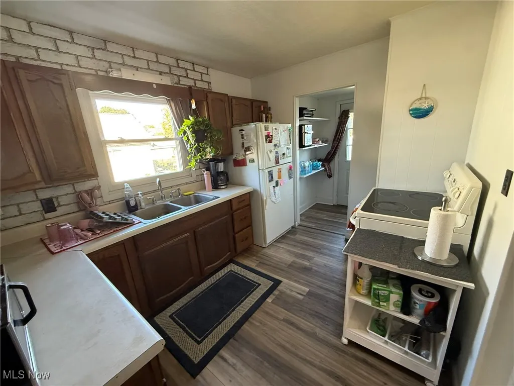 Kitchen with light countertops, white appliances, dark wood-type flooring, and backsplash