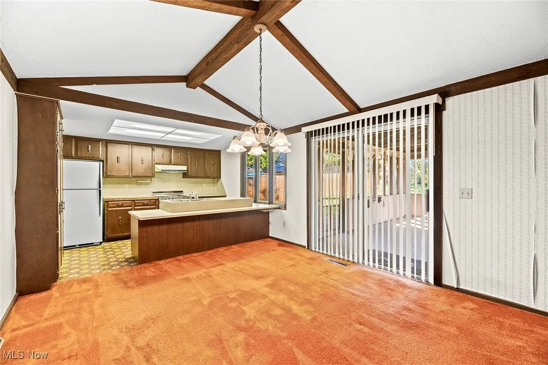Kitchen with light countertops, a chandelier, healthy amount of natural light, and freestanding refrigerator