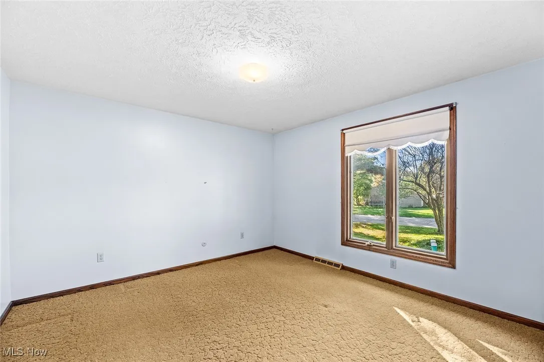 Empty room with a textured ceiling and baseboards