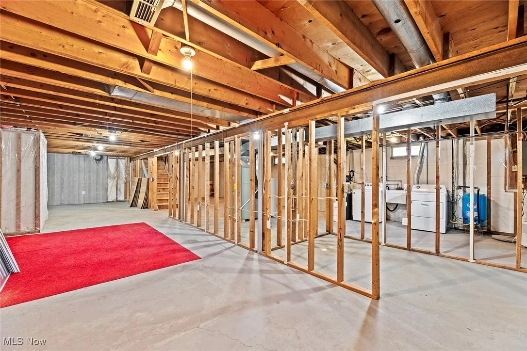 Unfinished basement with a water pressure tank and washing machine and dryer