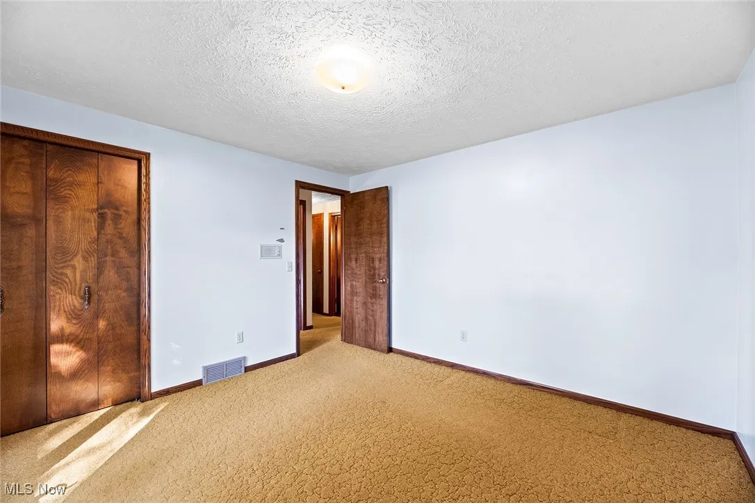 Unfurnished bedroom with carpet, a textured ceiling, and a closet