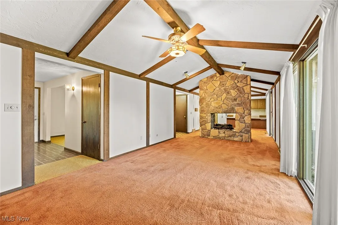 Unfurnished living room featuring light carpet, ceiling fan, and a fireplace
