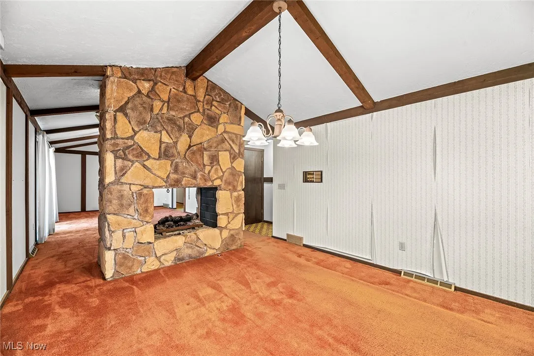 Unfurnished living room with carpet flooring, a fireplace, and a chandelier