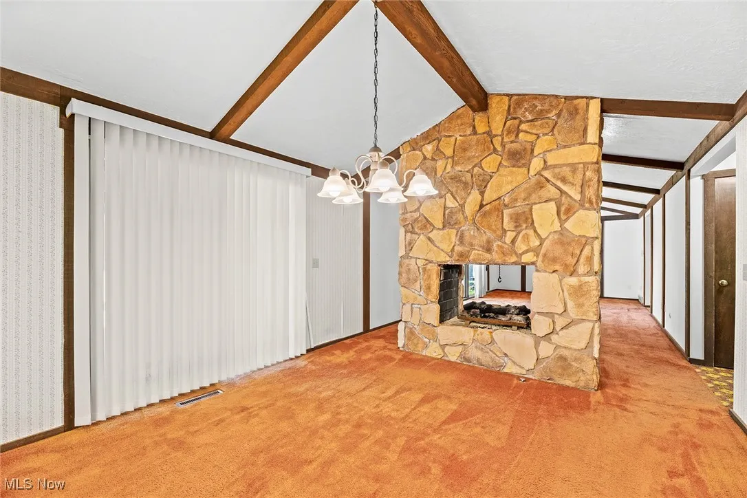 Unfurnished living room with a fireplace, carpet, and a chandelier