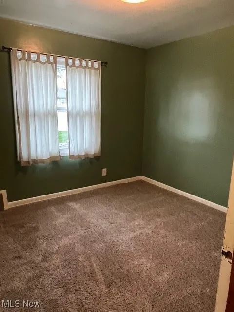Empty room featuring baseboards and carpet floors