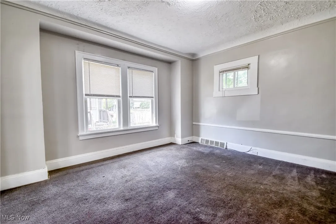 Carpeted empty room featuring a textured ceiling and baseboards