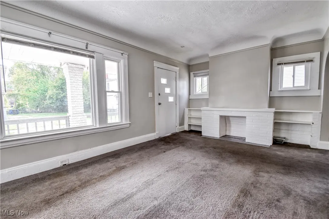 Foyer entrance with carpet, a fireplace, and a textured ceiling