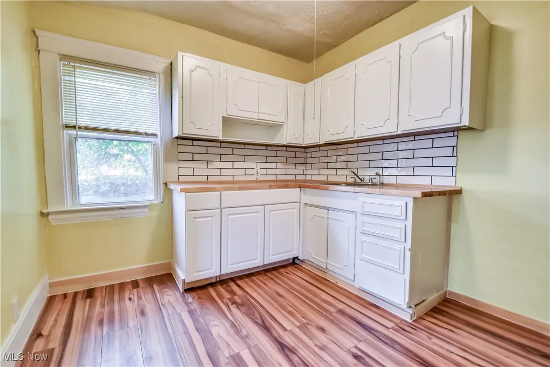 Kitchen with backsplash, white cabinetry, light wood-style floors, and wooden counters