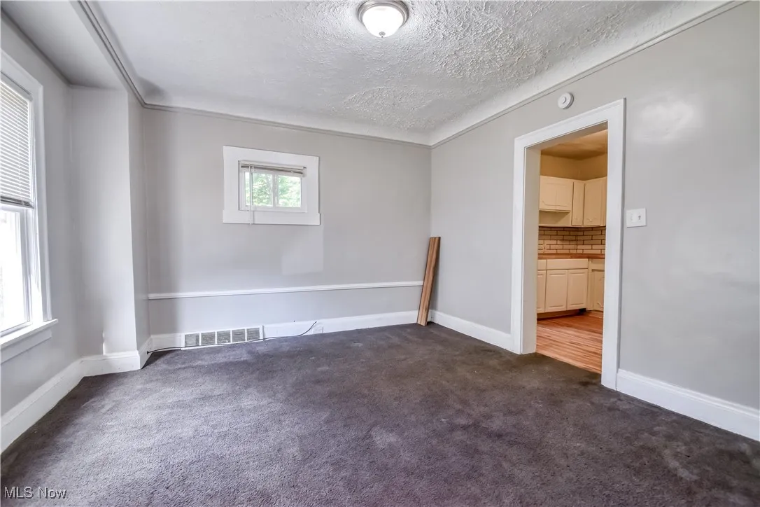 Empty room featuring dark carpet and a textured ceiling