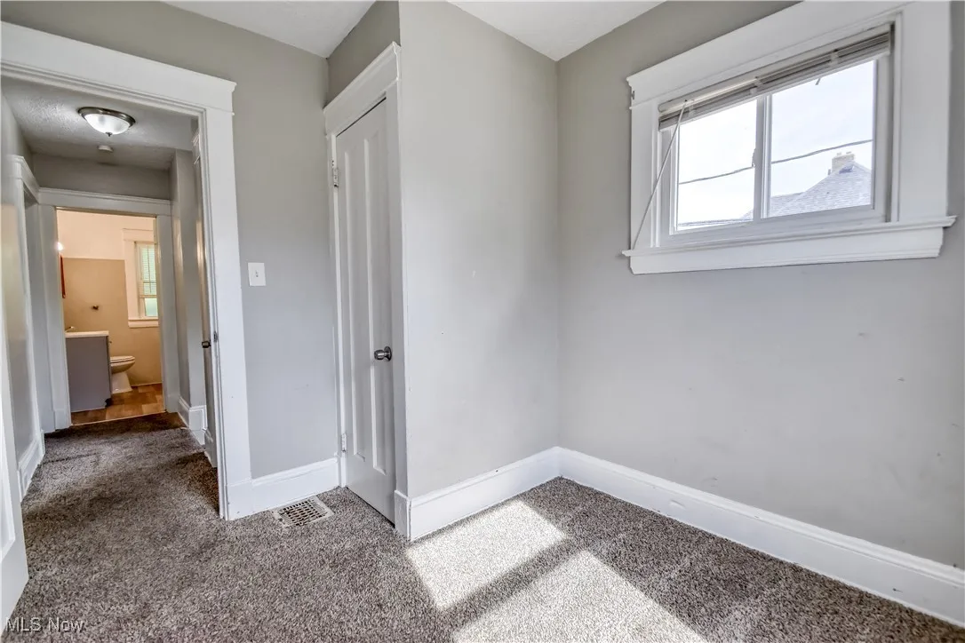 Unfurnished bedroom with multiple windows and carpet