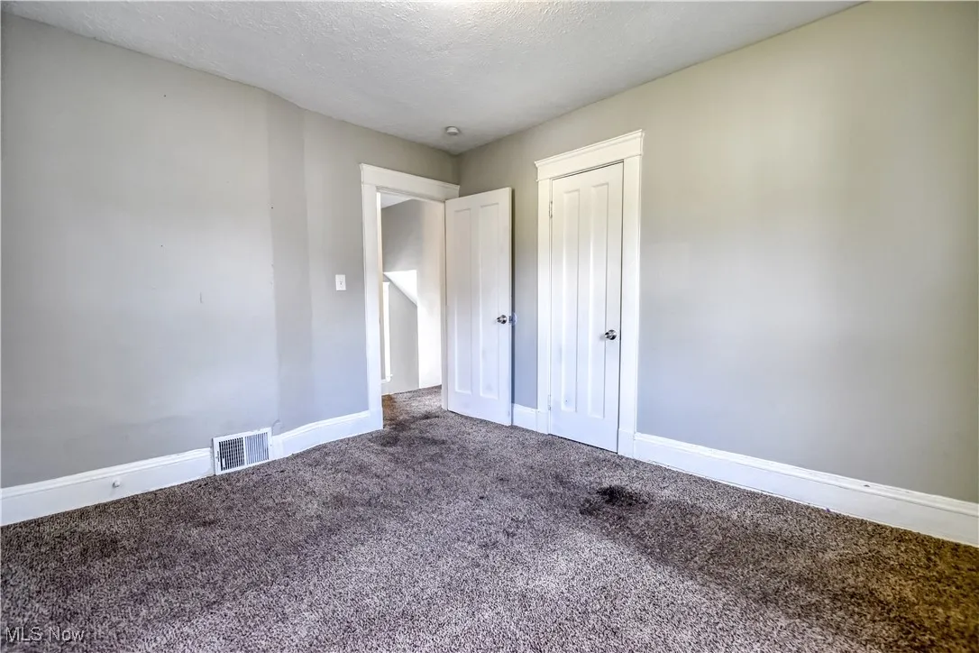 Unfurnished bedroom with a textured ceiling, carpet floors, and a closet