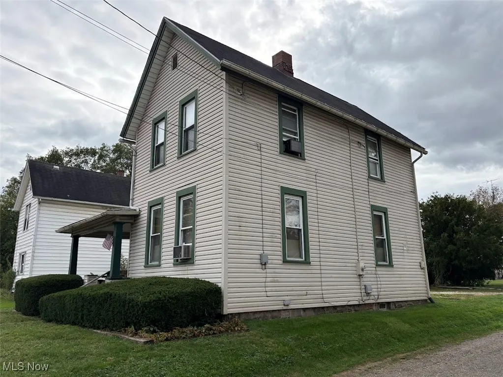 View of side of property with a lawn and a chimney