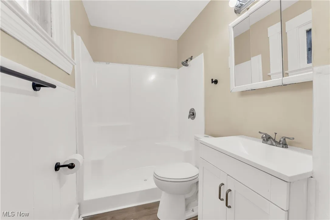 Bathroom with vanity, dark wood finished floors, and a shower