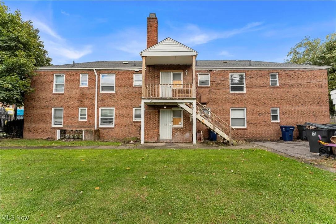 Back of property featuring a yard, stairway, brick siding, a balcony, and a patio area