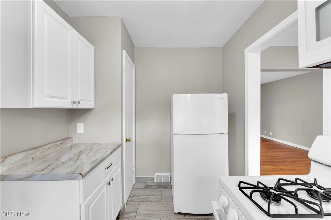 Kitchen featuring light countertops, white appliances, and white cabinetry