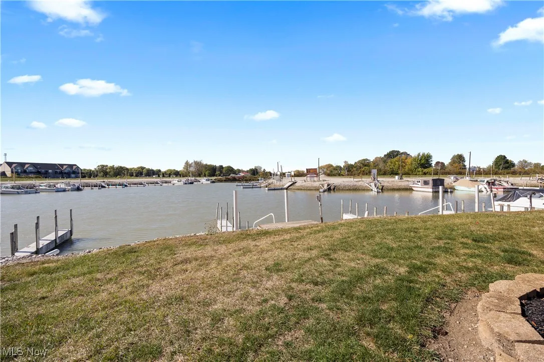 View of green lawn featuring a boat dock and a water view