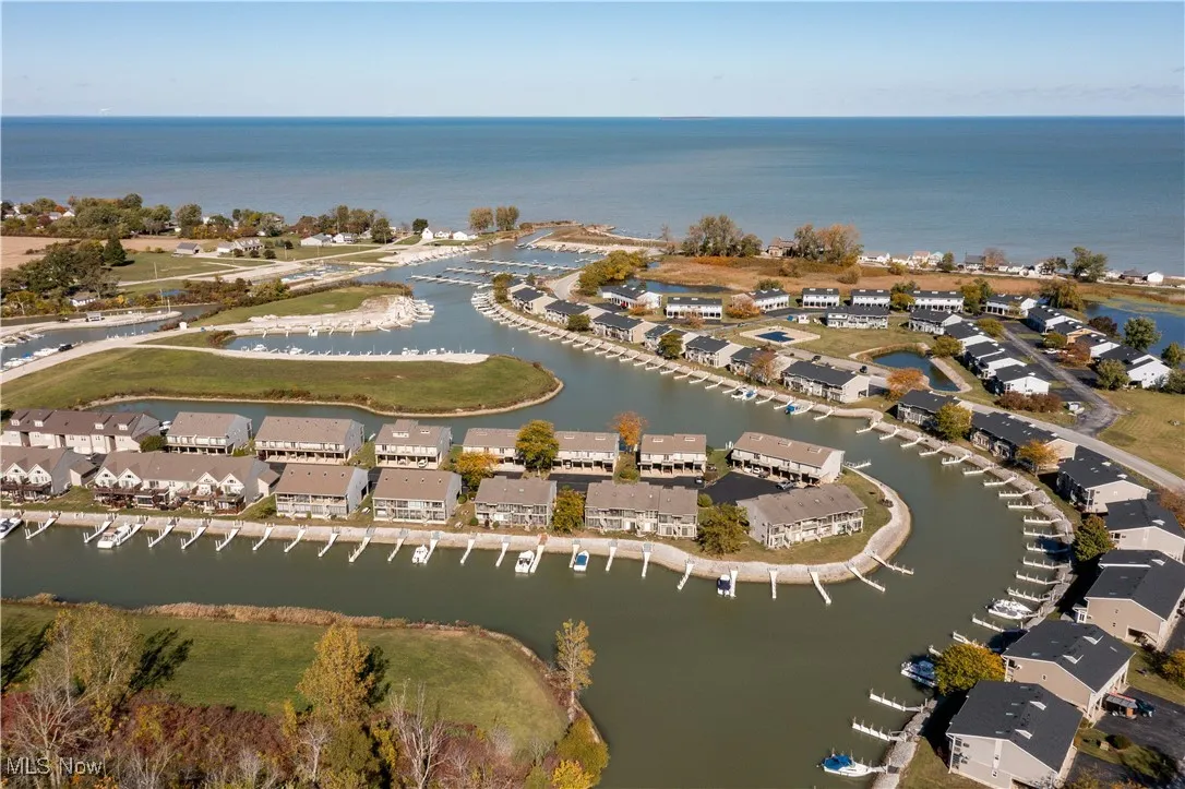 Aerial view of property and surrounding area featuring nearby suburban area and a large body of water