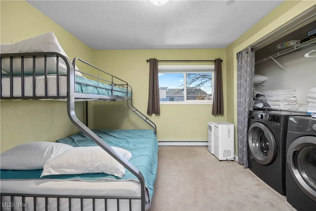 Bedroom with carpet, washer and clothes dryer, a closet, a textured ceiling, and baseboard heating