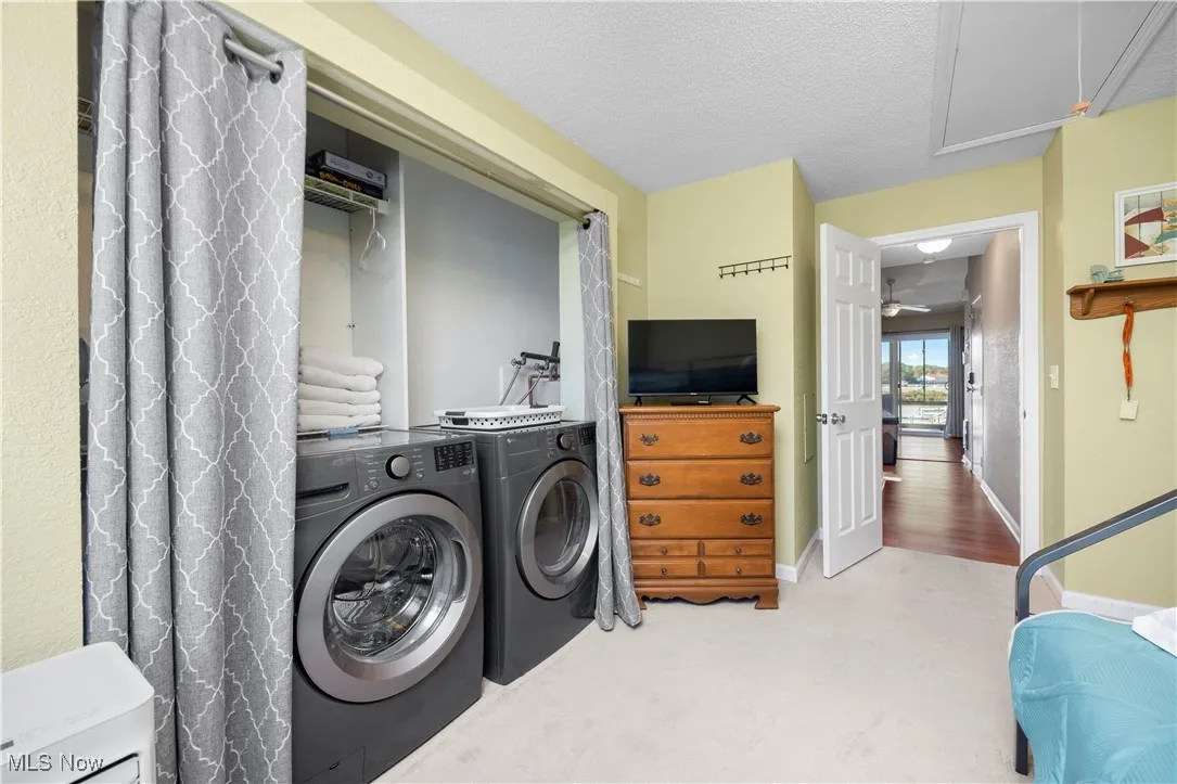 Laundry room featuring carpet flooring, independent washer and dryer, a textured ceiling, and attic access