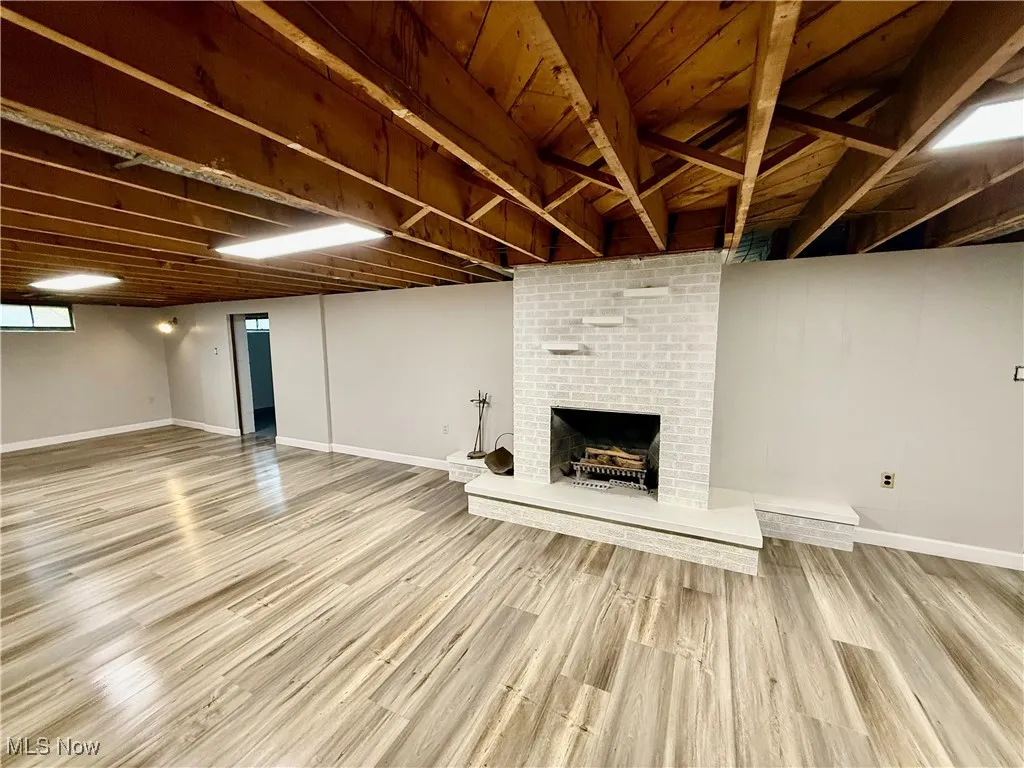 Finished basement featuring a brick fireplace and light wood-style flooring