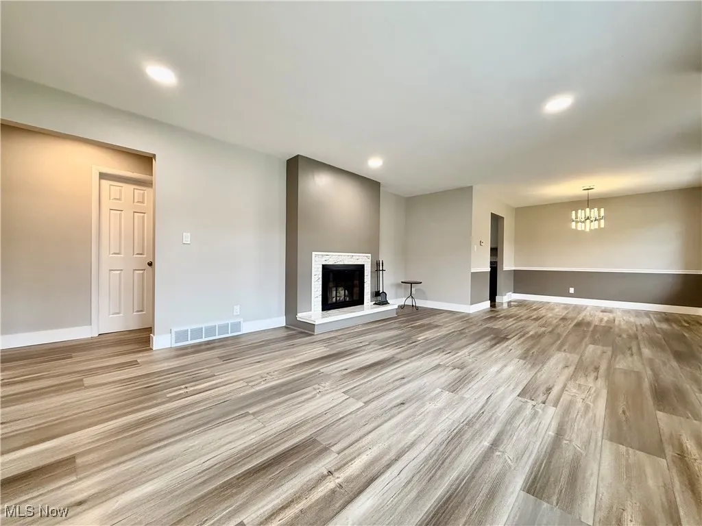 Unfurnished living room with light wood-style flooring, recessed lighting, and a fireplace with raised hearth