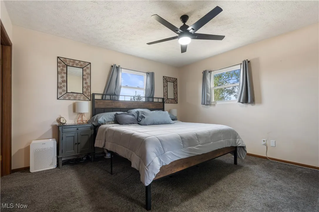 Carpeted bedroom featuring a textured ceiling and ceiling fan