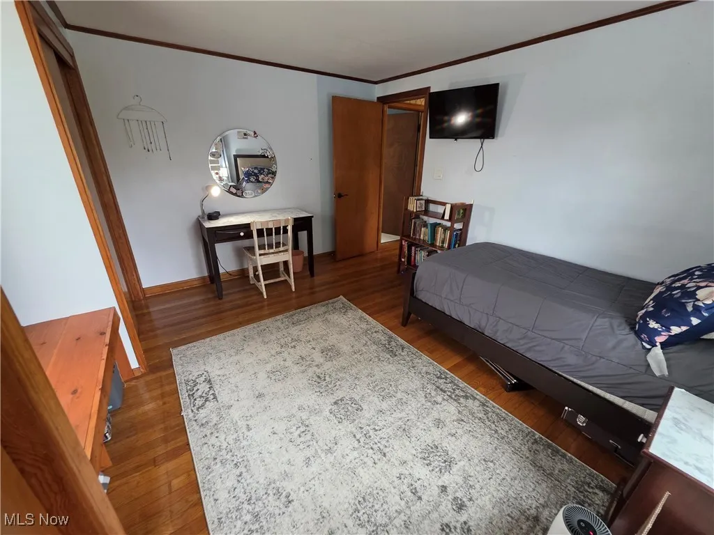 Bedroom with crown molding and wood finished floors
