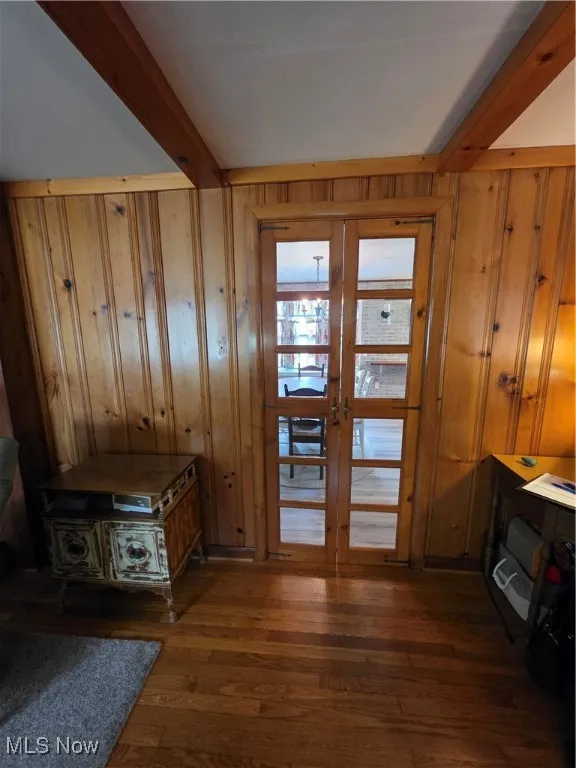 Entryway with beam ceiling, dark wood-style flooring, wood walls, and french doors