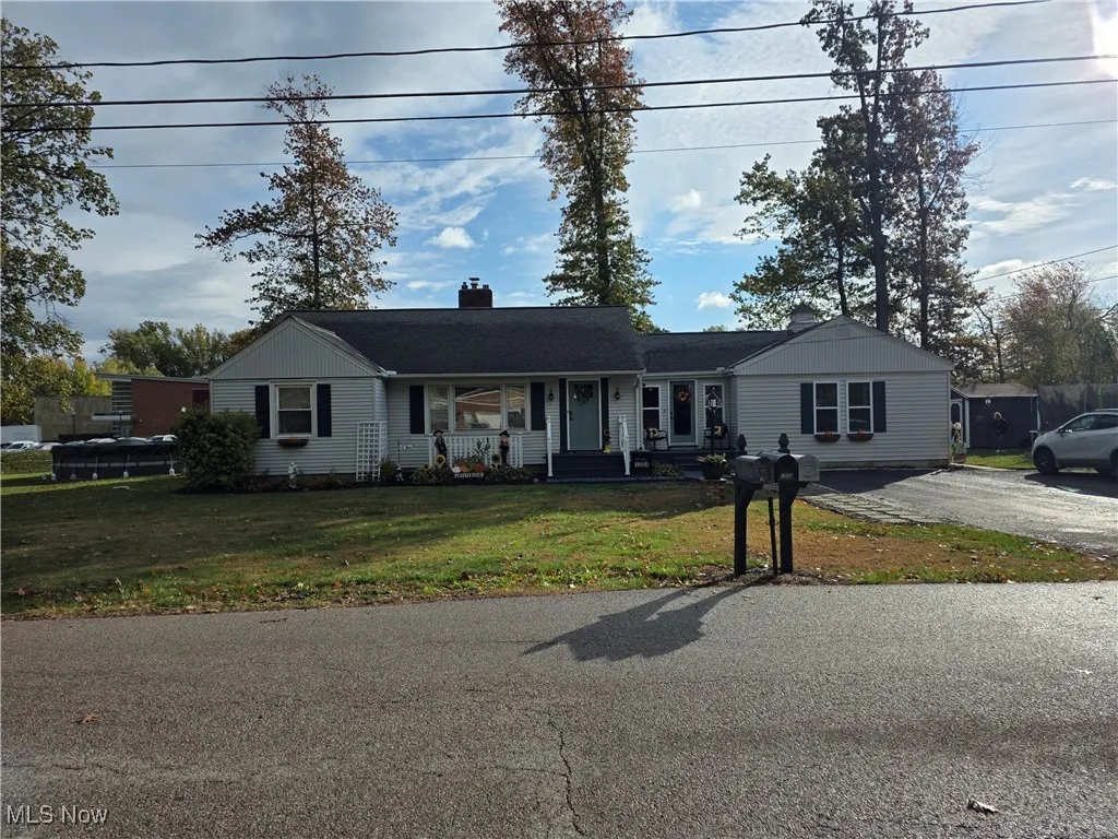 Ranch-style house featuring a porch, a front yard, a chimney, and driveway