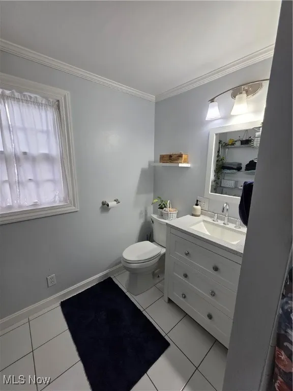 Bathroom with ornamental molding, vanity, and light tile patterned floors