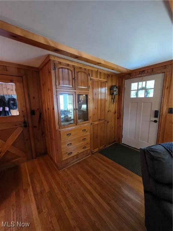 Entryway featuring dark wood-style floors, wooden walls, and beamed ceiling
