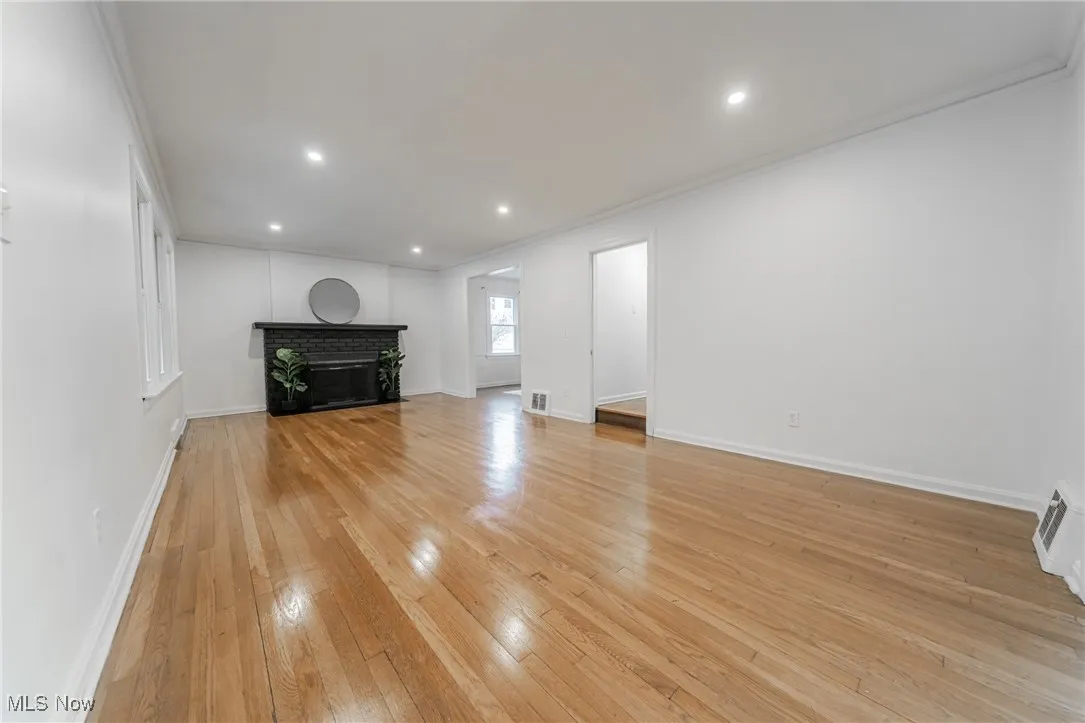 Unfurnished living room featuring light wood finished floors, recessed lighting, a fireplace, and crown molding