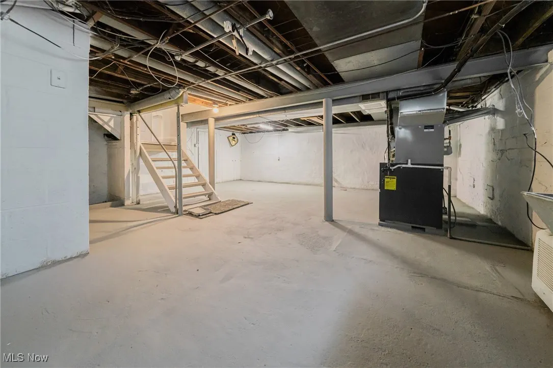 Unfinished basement featuring stairway and heating unit