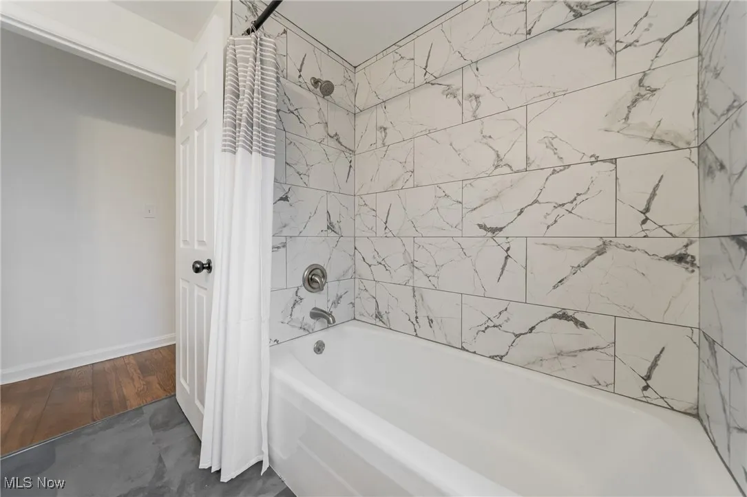Full bathroom with shower / bath combination with curtain and baseboards