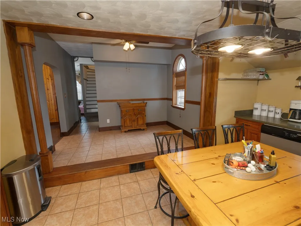 View from kitchen looking into the breakfast nook with ceramic tile floors, a ceiling fan, and arched walkways