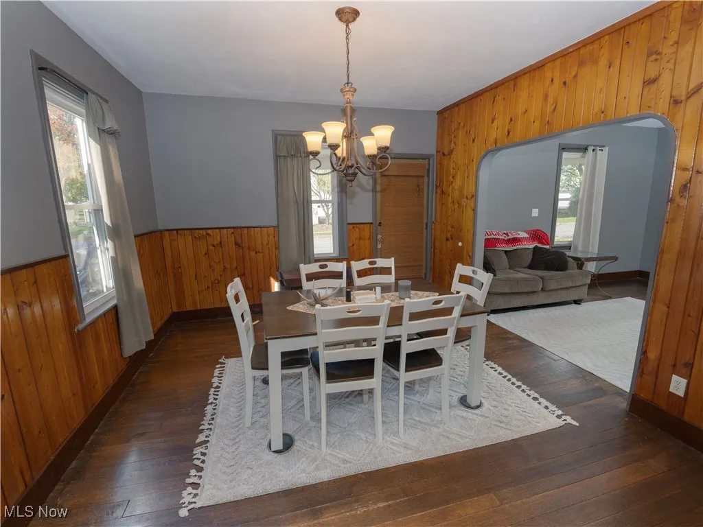 Dining area with wooden walls, wood flooring, wainscoting, and a chandelier