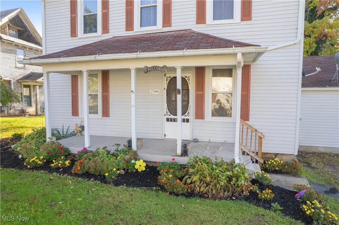 Property entrance with a covered front porch and a shingled roof