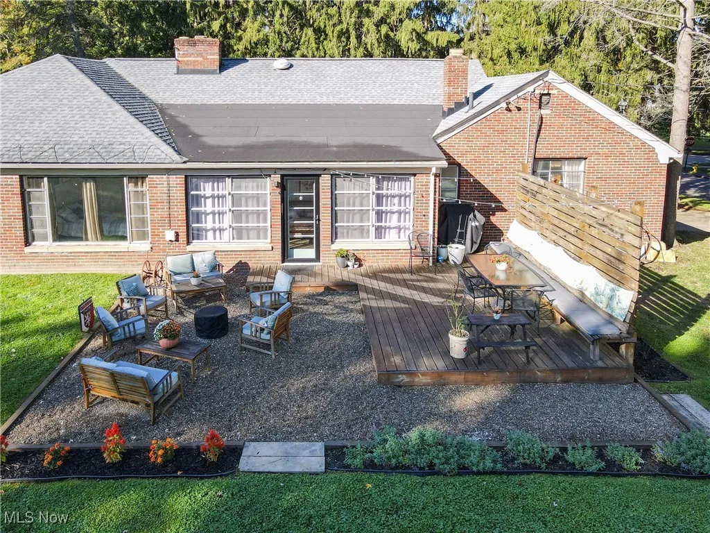 Rear view of house with a chimney, brick siding, outdoor lounge area, roof with shingles, and a yard