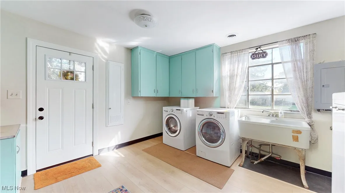 Laundry area featuring healthy amount of natural light, electric panel, separate washer and dryer, and light wood-style floors