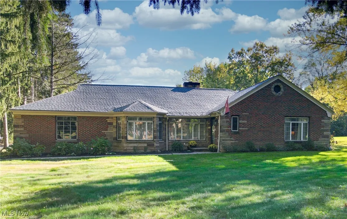 Ranch-style house with a front yard, a sunroom, a chimney, and brick siding
